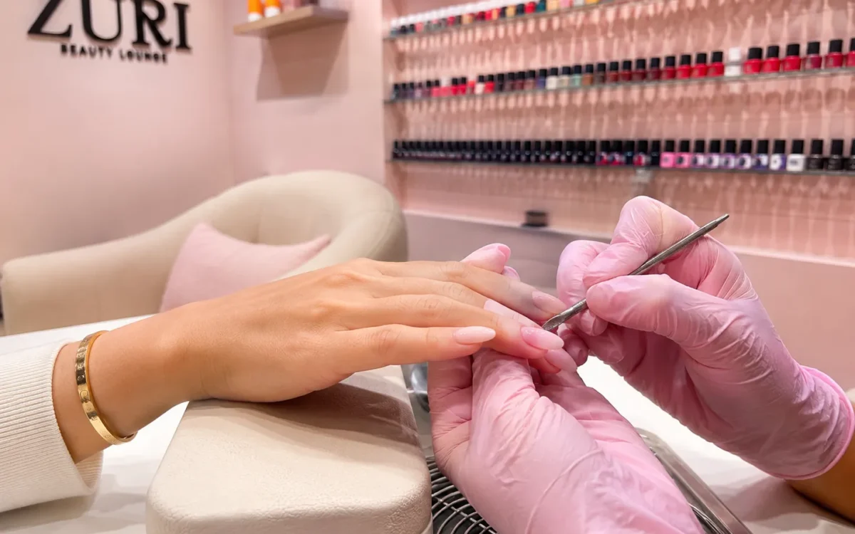 Nail technician applying gel polish during a manicure
