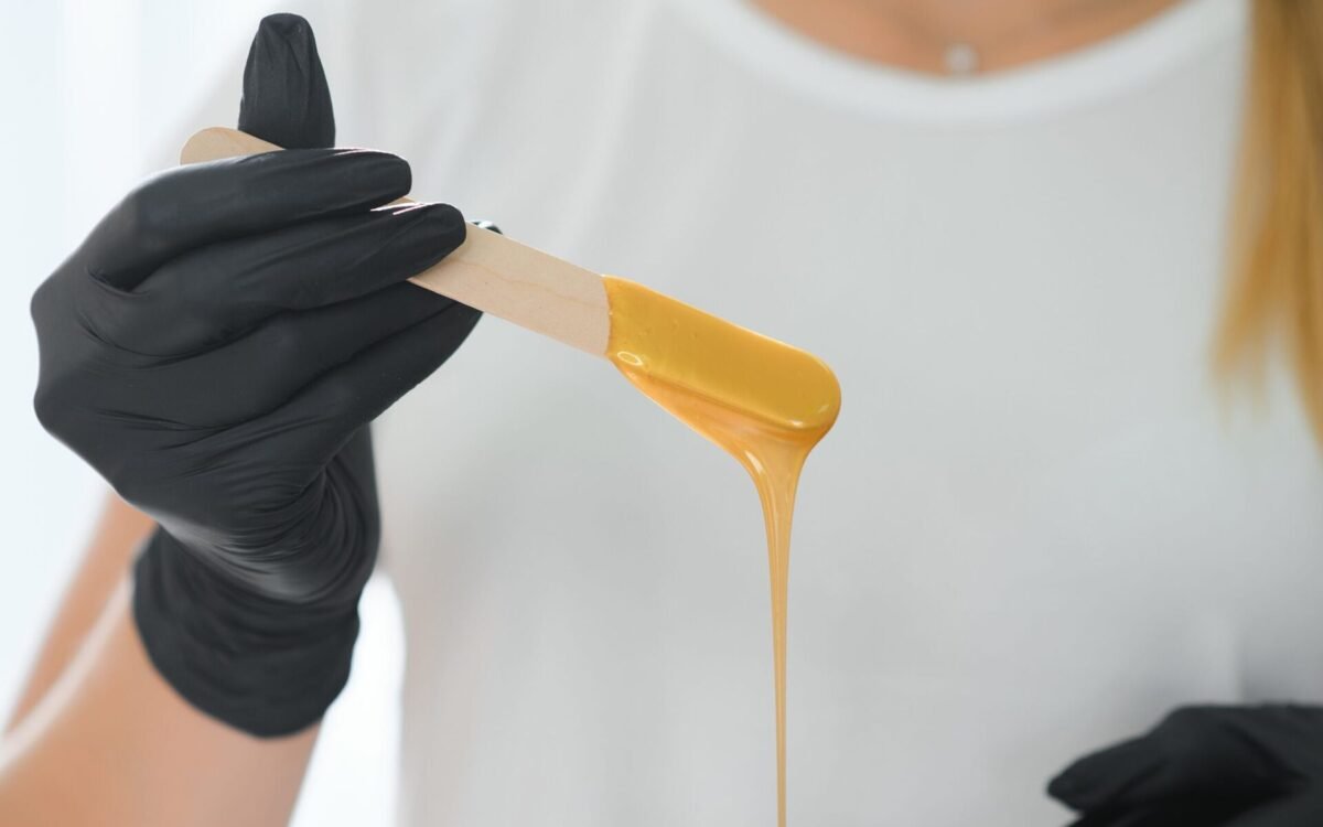 Esthetician holding a waxing stick coated in warm wax