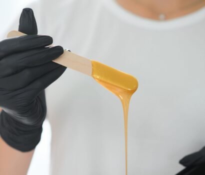 Esthetician holding a waxing stick coated in warm wax